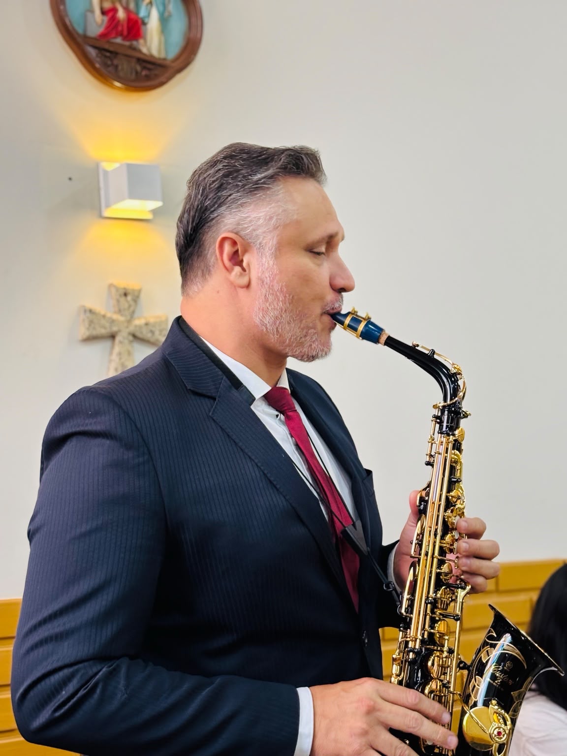 Saxofonista do grupo tocando em uma cerimônia religiosa